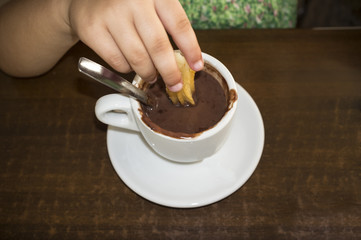 Cute little girl eating churros with hot chocolate