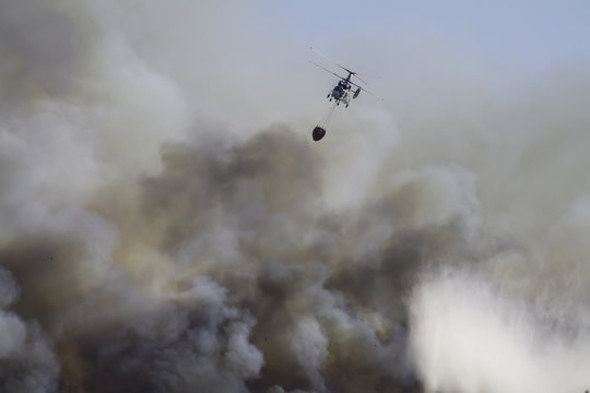 Wild fire close to houses being fought with airplanes and helicopters