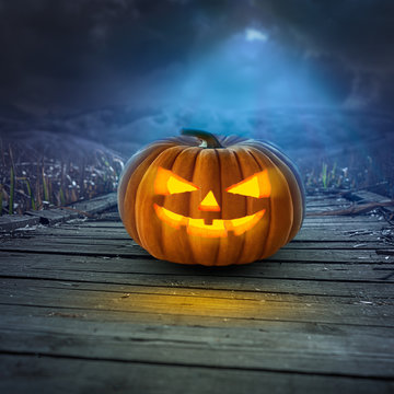 Spooky Halloween pumpkin on wooden path at night