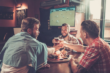 Friends drinking beer and watching soccer in a pub