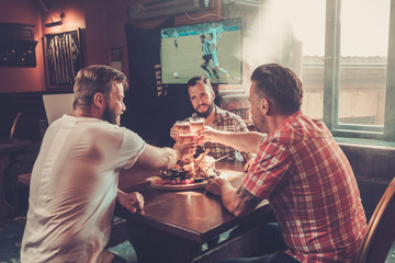 Friends drinking beer and watching soccer in a pub