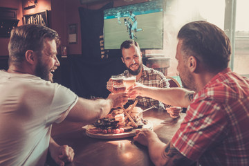 Friends drinking beer and watching soccer in a pub