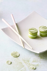 Upside Down Matcha Yuzu Macarons on white square plate, on light background.