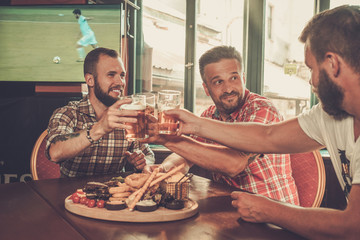 Friends drinking beer and watching soccer in a pub