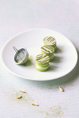 Upside Down Matcha Yuzu Macarons on white oval plate, on light background.