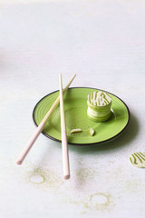 Upside Down Matcha Yuzu Macaron on green plate, on light background.