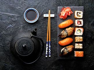 Variation of sushi and rolls on stone table. Sushi rolls, sashimi set with chopsticks. Top view...