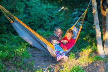 Joyful teenagers - brother and sister ride in a hammock