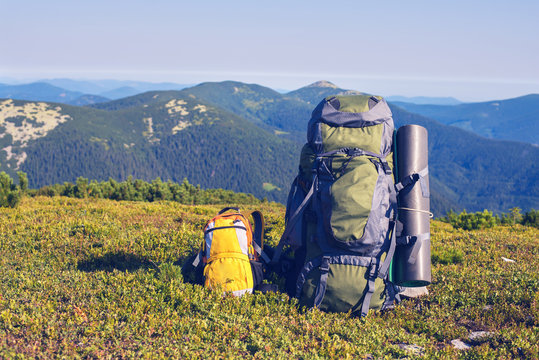 Large backpack for an adult stands next to a small yellow backpack