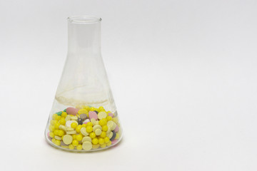 Erlenmeyer flasks, filled with tablets and dragee. On white background
