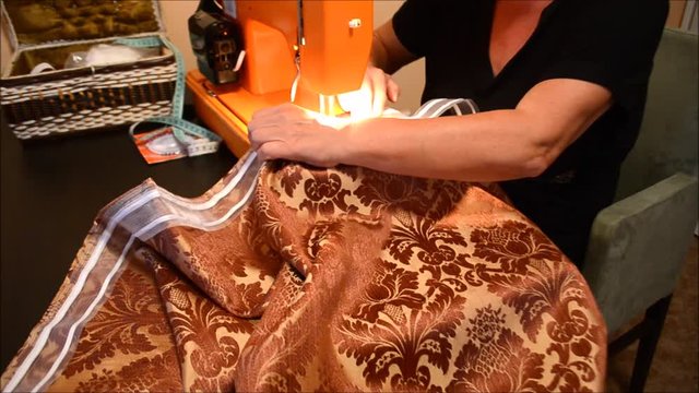 Senior female crafter sewing a drape at night in her home