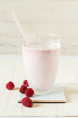 Yogurt smoothie with raspberries in glass on wooden table