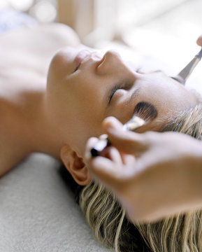 A woman receiving holistic facial massage at spa