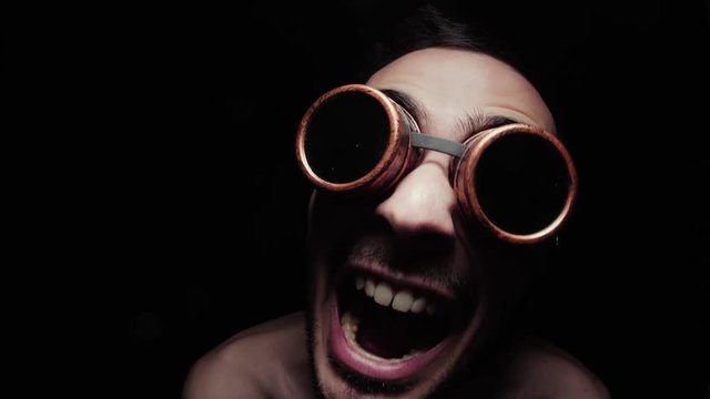 Man making strange funny faces to the camera. Closeup on his portrait with dark background.