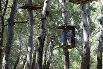 Mother and son enjoying in a climbing adventure high wire park between trees. Active family, love trust, support and togetherness concept