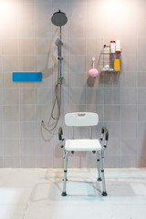Padded shower chair with arms and back in bathroom with bright tile wall and floor.