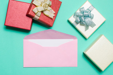 Pink envelope with blank white card and gift box for giving on color background