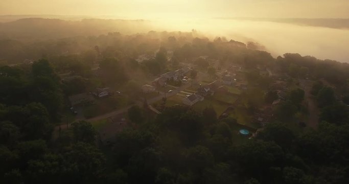 An early foggy morning forward aerial establishing shot of a typical Western Pennsylvania residential neighborhood. Pittsburgh suburb.  	