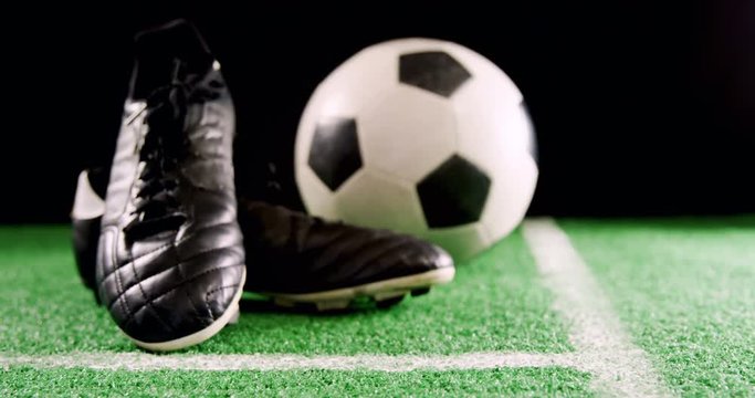 Close-up of football and cleats on artificial grass 