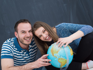 couple in casual clothing investigating globe