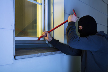 Burglar Using Crowbar To Break Into A House