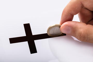 Hand Inserting Coin In Crucifix Slot