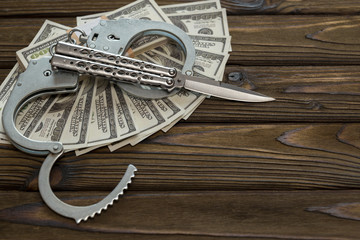 Financial Crime Concept Knife, Handcuffs, Money. On a wooden table background