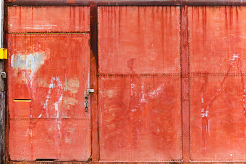 Old rusty red steel front gate security door with three heavy metal padlocks