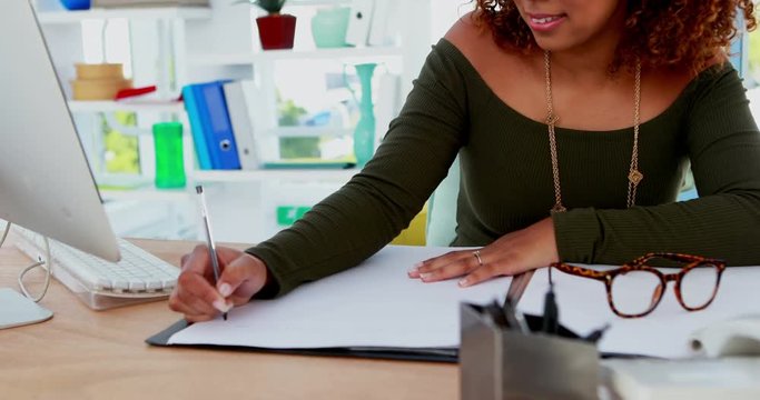 Female executive writing on a document while listening music 