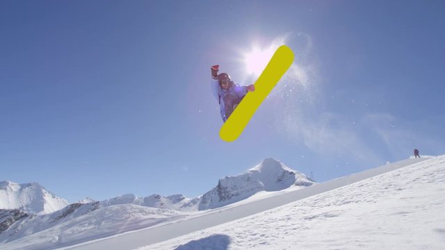 SLOW MOTION: Young pro snowboarder riding the half pipe in big mountain snow park, performing spraying trick on halfpipe wall lip in sunny winter 