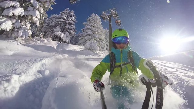 SLOW MOTION CLOSE UP PORTRAIT: Extreme freestyle skier skiing down the mountain slope in fresh powder snow on a beautiful sunny way in winter