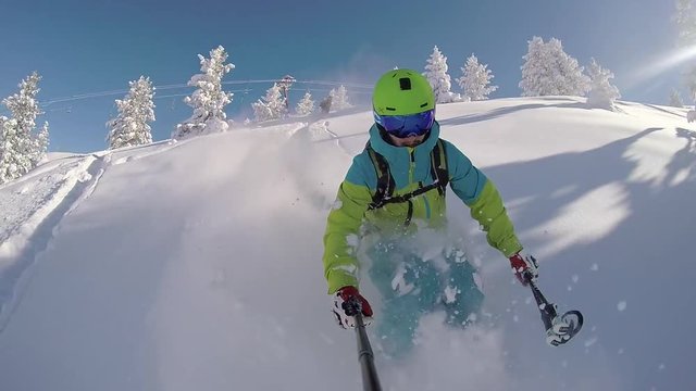 SLOW MOTION CLOSE UP PORTRAIT: Extreme freestyle skier skiing down the mountain slope in fresh powder snow on a beautiful sunny way in winter
