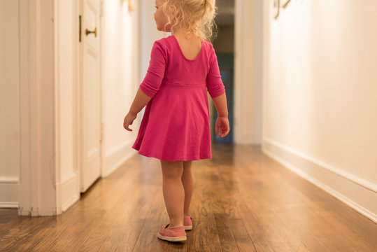 Little Girl In Pink Dress Walking Down Empty Hallway In An Old House