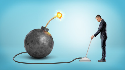 A small businessman turning a metal lever connected to a large iron bomb with a lit fuse.