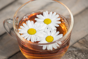 Herbal tea with chamomile on a wooden table on a summer sunny morning