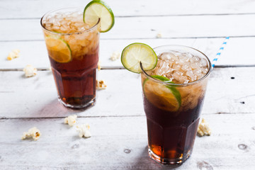Cola drink with lemon lime in glass on white table