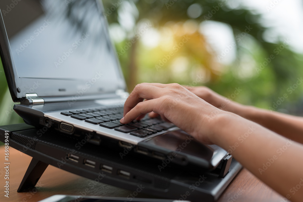 Poster woman's hands on keyboarding while working messaging via social networks using computer laptop. back