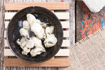 Opened Oysters on dark bowl on  wood background