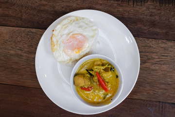 Green curry with Rice and Egg served on a wooden table.