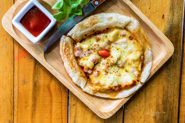 Hot pizza slice with melting cheese on a rustic wooden table.