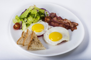 Fried eggs with bacon and vegetables