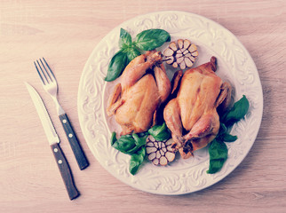 whole roasted chicken with bound with twine the feet on the plate with Basil and garlic