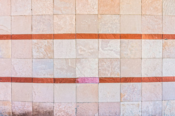 Curved natural stone wall with color strips. It is constructed with tiles.