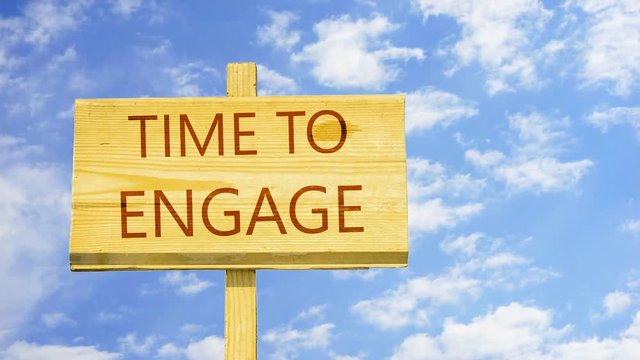 Time to engage. Words on a wooden sign against time lapse clouds in the blue sky. 