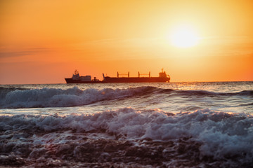 Sun setting at the sea with sailing cargo ship, sunrise view