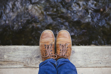 feet standing on wooden bridge edge over river travel lifestyle concept summer vacations