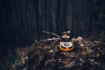 Yellow old school compass laying on the stone in mountain forest, ready to travel