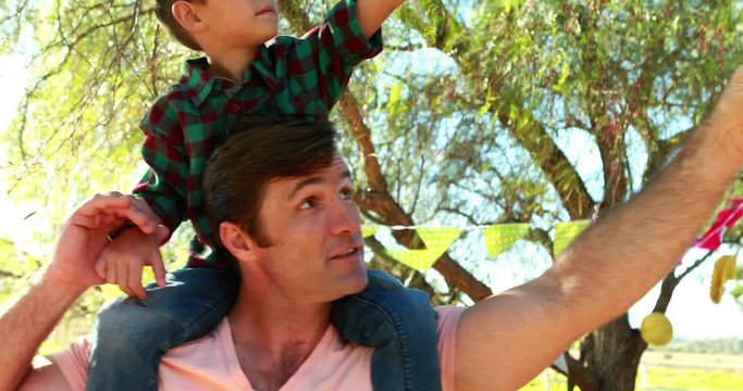Happy father carrying his son on shoulder in park 