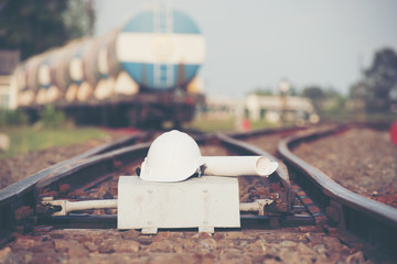 White helmet With the project plan  on the railroad tracks  with container trains on railways track in logistic station background.
