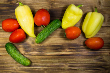 Tomatoes, cucumbers and peppers on wooden background